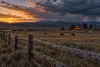 Un ranch bovin générique sous un ciel d’orage au coucher du soleil.